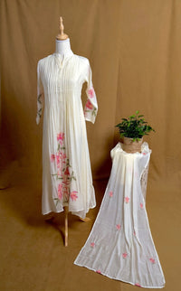 White embroidered dress on a mannequin with another dress on a brown background