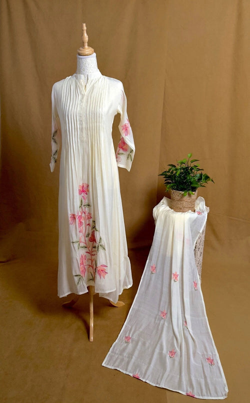 White embroidered dress on a mannequin with another dress on a brown background