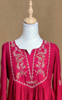 Red dress with floral embroidery on a mannequin against a brown background