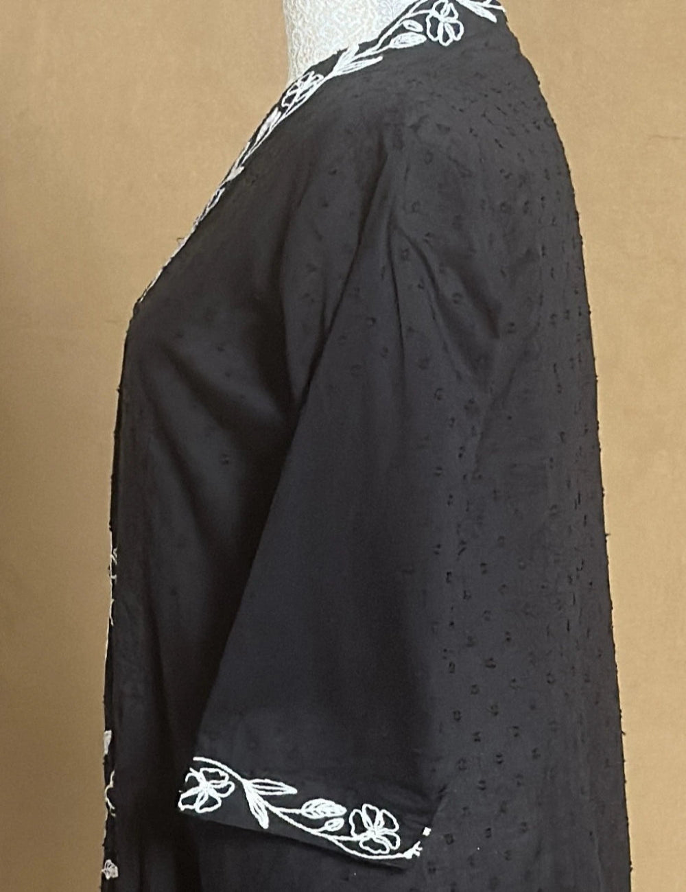 Black garment with white floral embroidery on a brown background