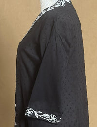 Black garment with white floral embroidery on a brown background