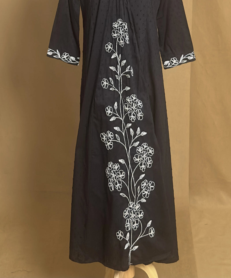 Black dress with white floral embroidery on a brown background