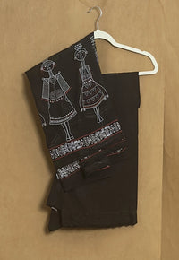 Black fabric with white embroidery on a hanger against a brown background