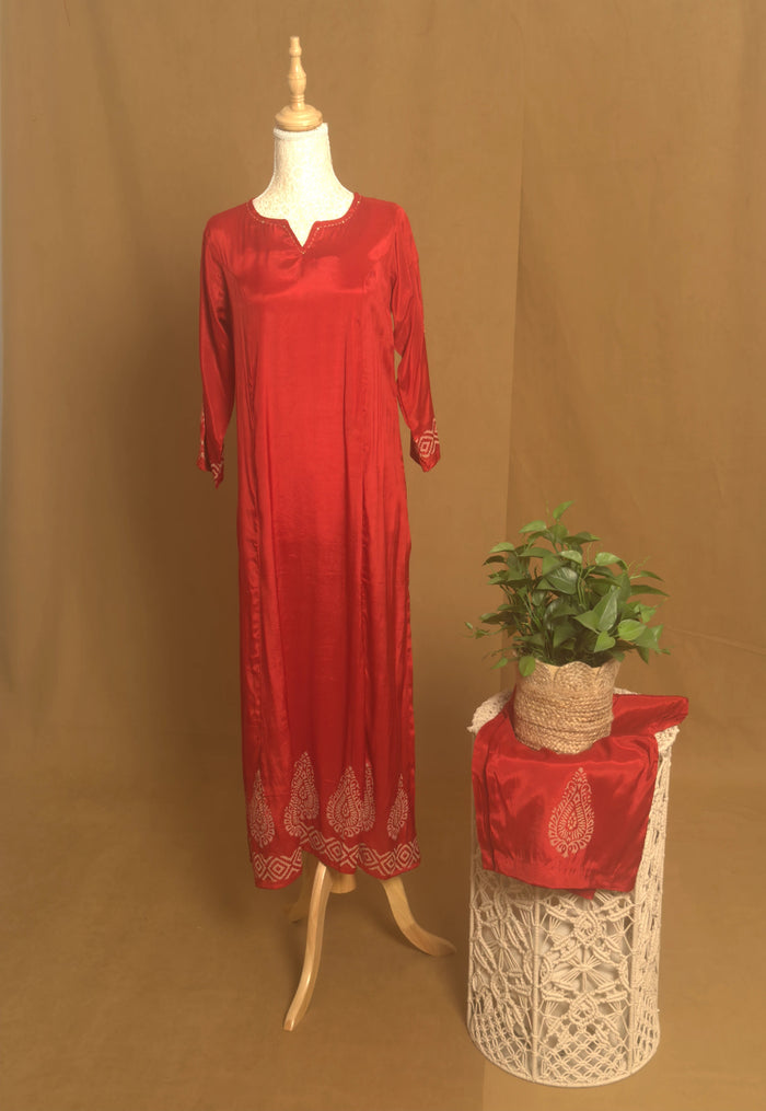 Red dress on a mannequin next to a plant on a textured surface