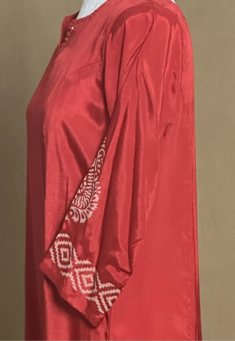 Red long-sleeve top with intricate white patterns on a brown background