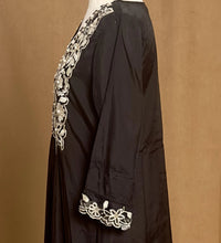 Black garment with white embroidery on a brown background