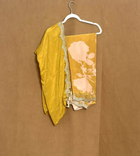 Yellow saree with floral design and gold border on a hanger against a brown background