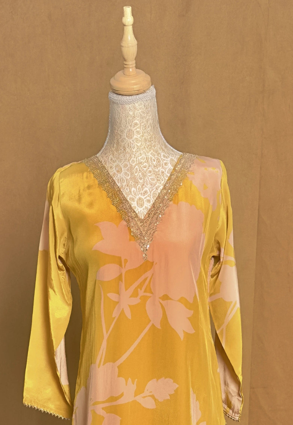 Yellow floral blouse on a mannequin against a brown background