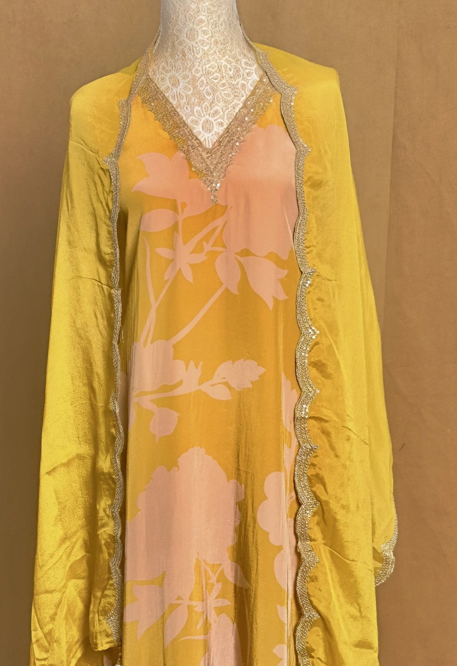 Yellow floral dress on a mannequin against a brown background