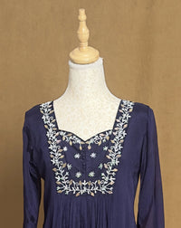 Navy blue dress with white embroidery on a mannequin against a brown background