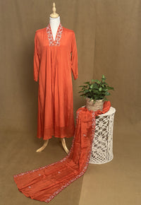 Orange dress with floral embroidery on a mannequin against a brown background