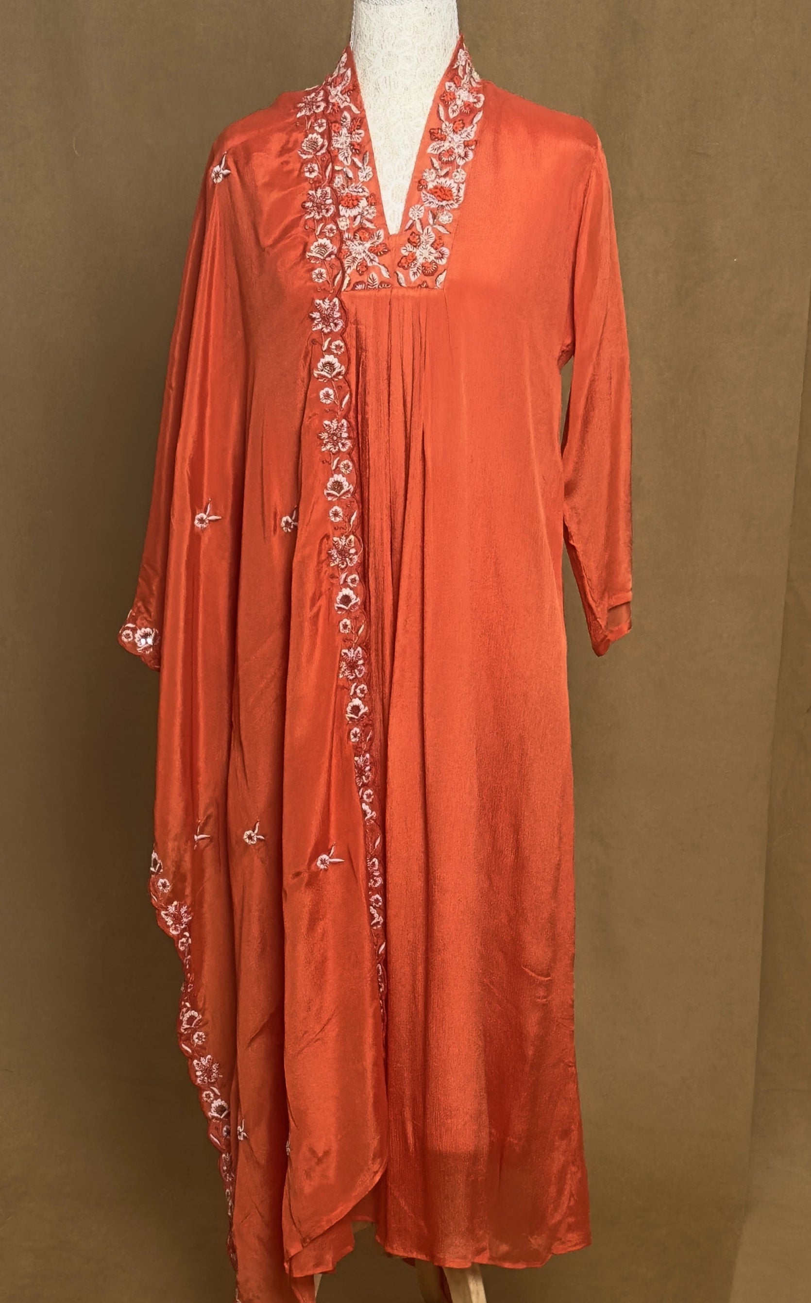 Red embroidered dress on a mannequin against a brown background