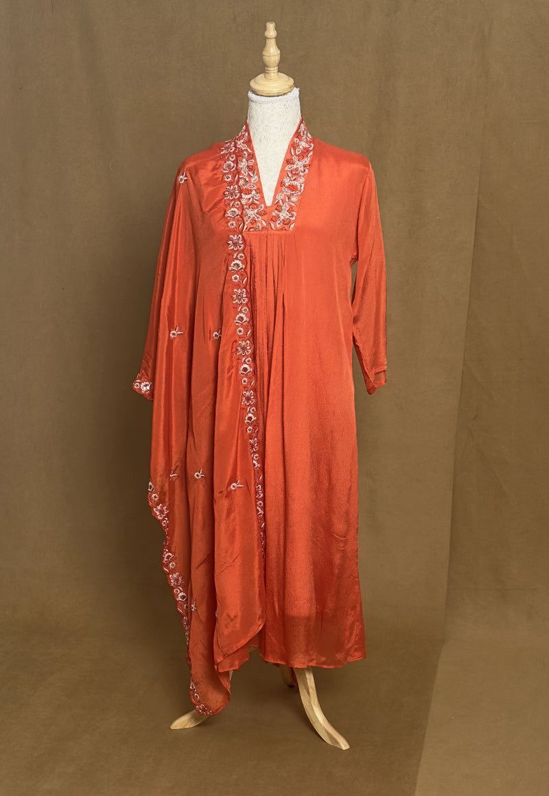 Orange dress with embroidery on a mannequin against a brown background