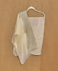 White dress with embellishments on a hanger against a brown background