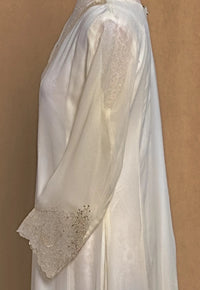 White lace dress with intricate detailing on a brown background