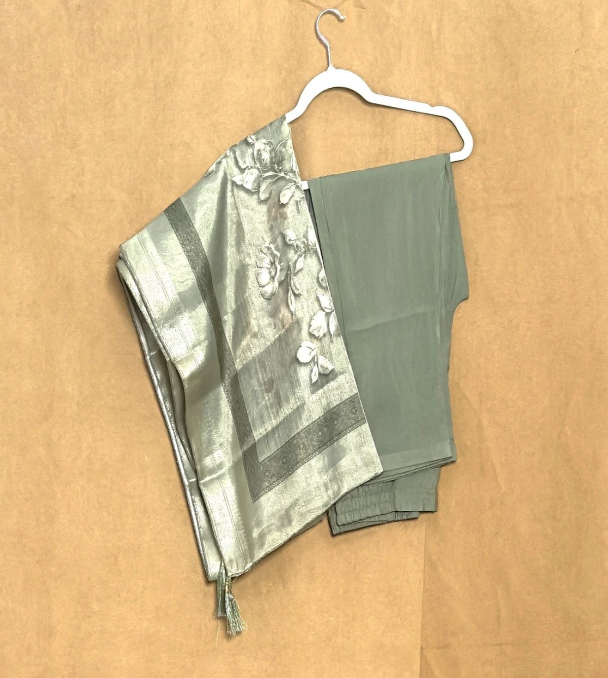 dress pant and shawl  on a hanger against a beige background