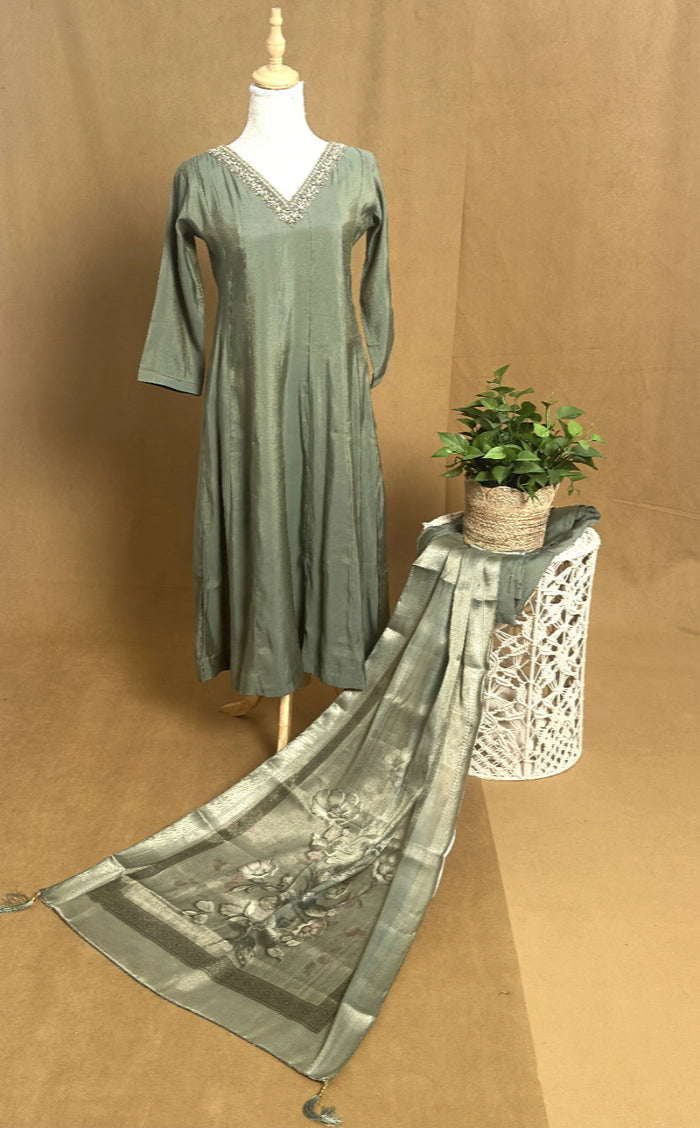 Green dress on a mannequin with a matching scarf draped over it against a brown background