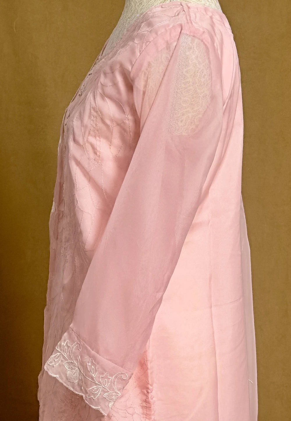 Pink lace garment on a mannequin against a brown background