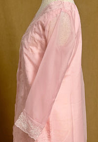 Pink lace garment on a mannequin against a brown background
