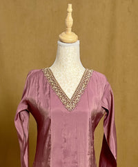 Pink blouse with intricate beading on a mannequin against a beige background