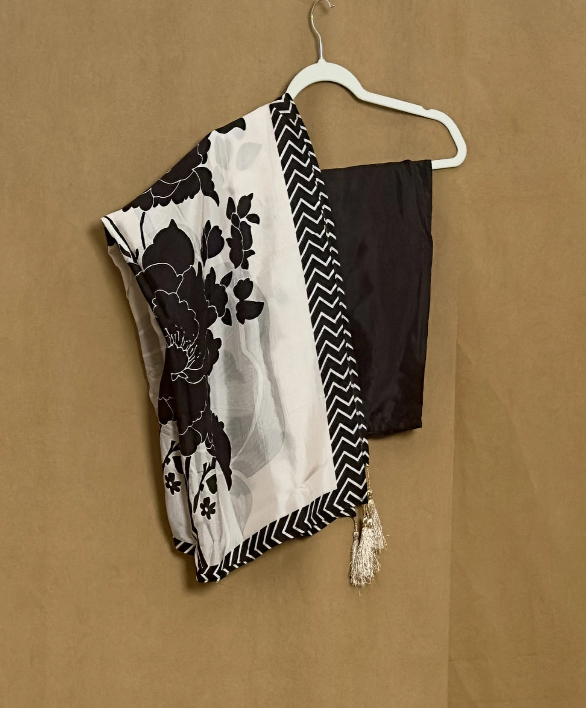Black and white floral scarf with a zigzag pattern draped over a black top on a beige background