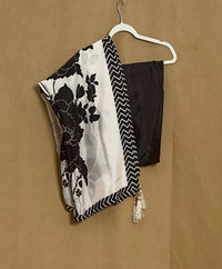 Black and white floral scarf with a zigzag pattern draped over a black top on a beige background