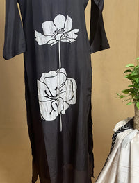 Black dress with white floral designs on a beige background