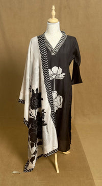 Mannequin wearing a black and white floral dress with a geometric pattern on a brown background