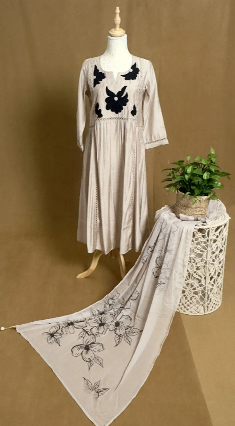 Mannequin wearing a beige dress with black floral embroidery on a brown background