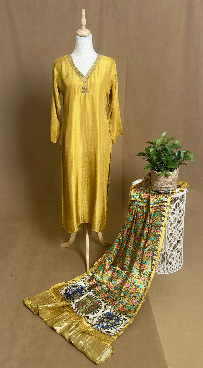 Yellow dress on a mannequin with a floral scarf and plant on a brown background