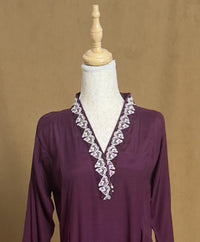 Purple blouse with white lace details on a mannequin against a brown background