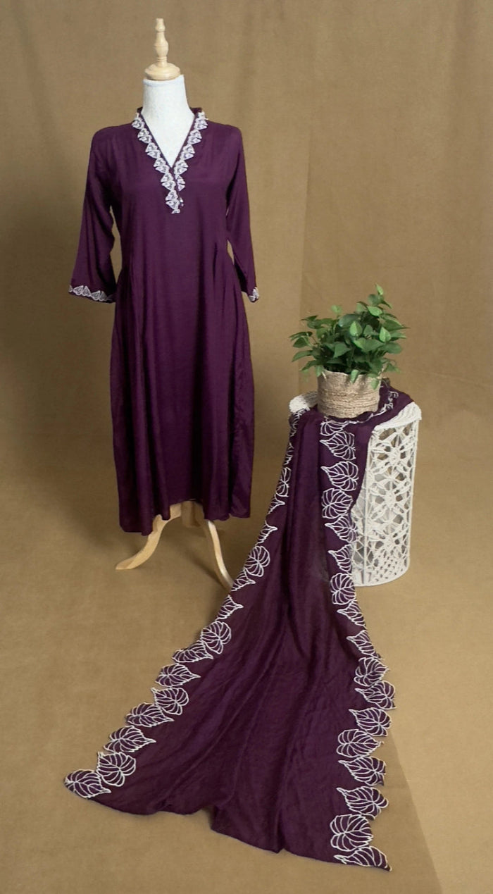 Purple dress with lace trim on a mannequin and on a table against a brown background