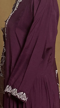 Close-up of a purple dress with white lace detailing on a brown background