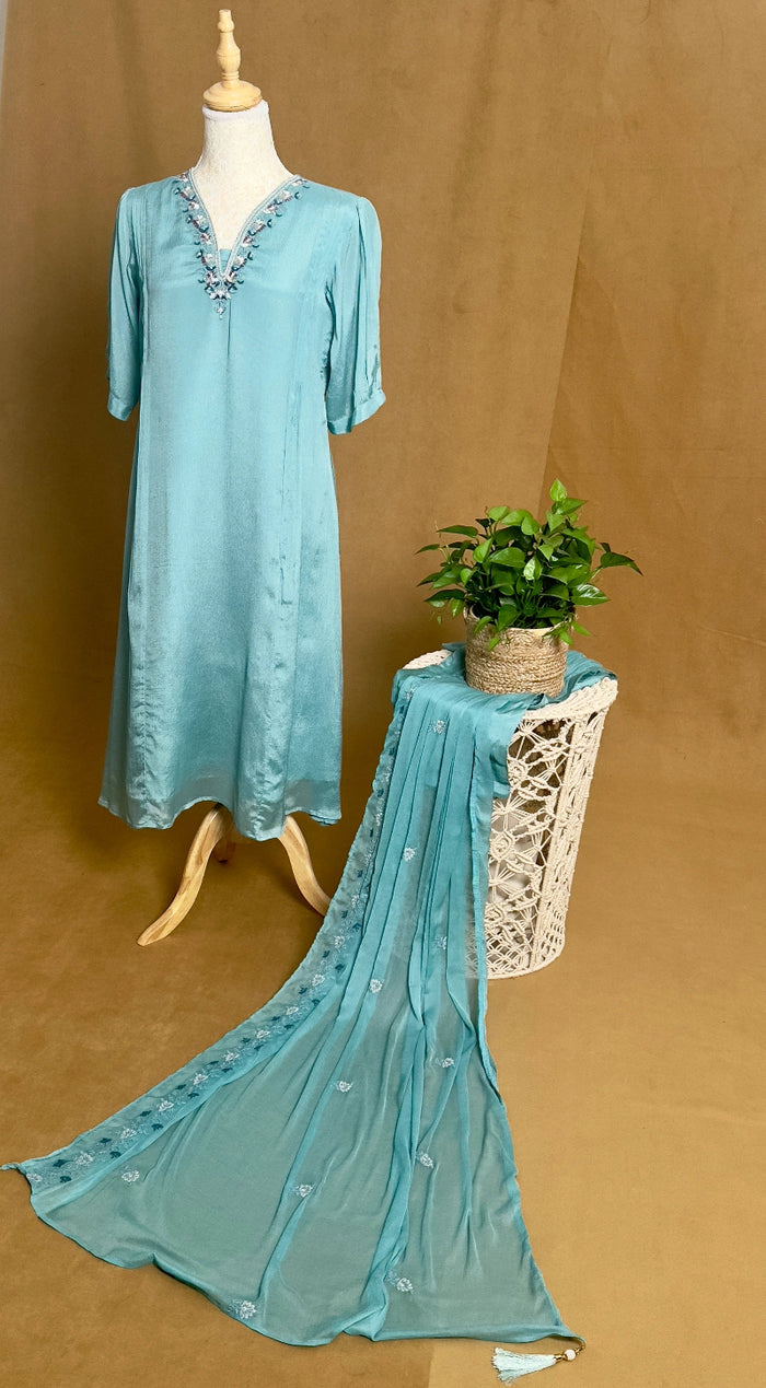 Teal dress with lace details on a mannequin against a brown background