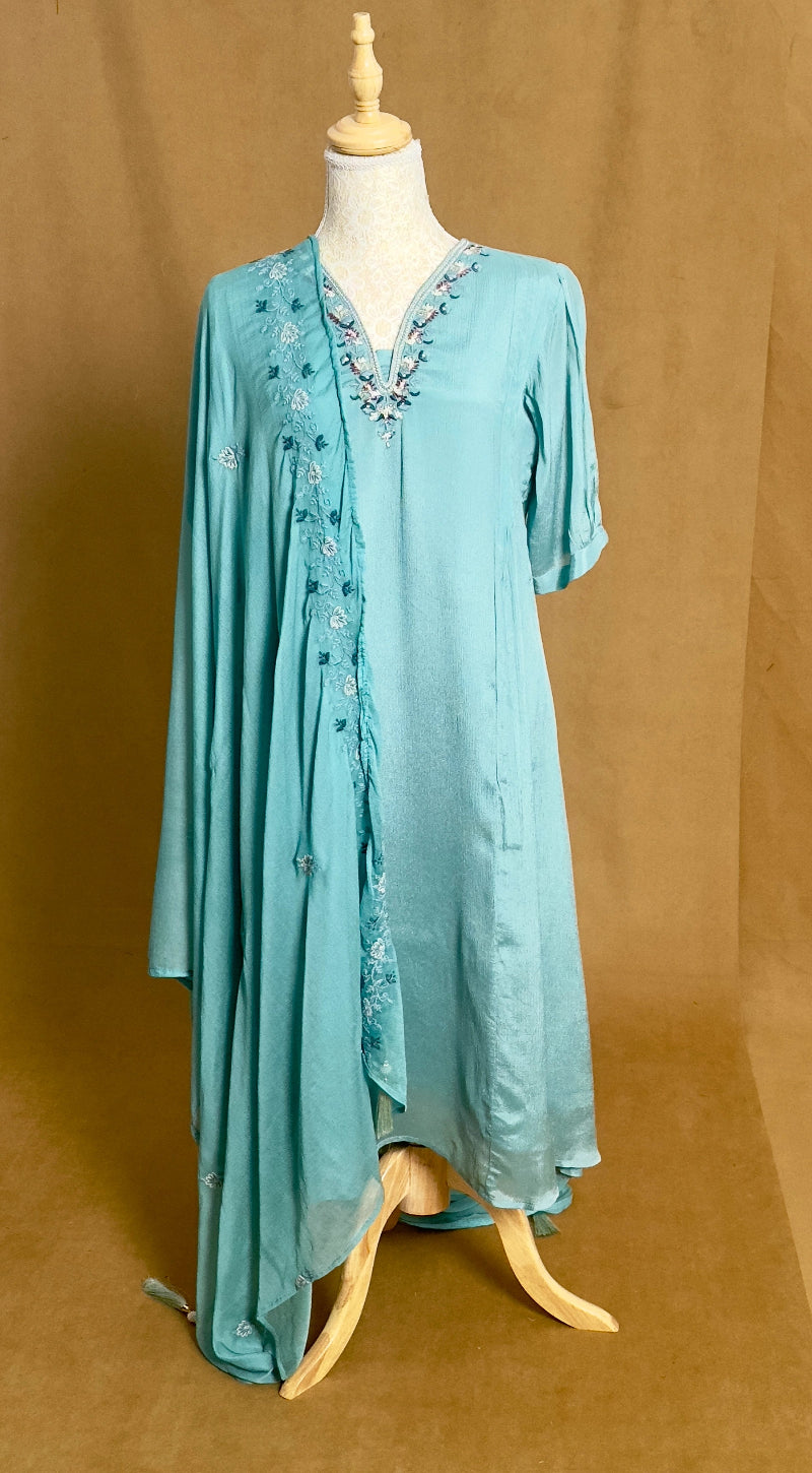 Turquoise dress with floral embroidery on a mannequin against a brown background
