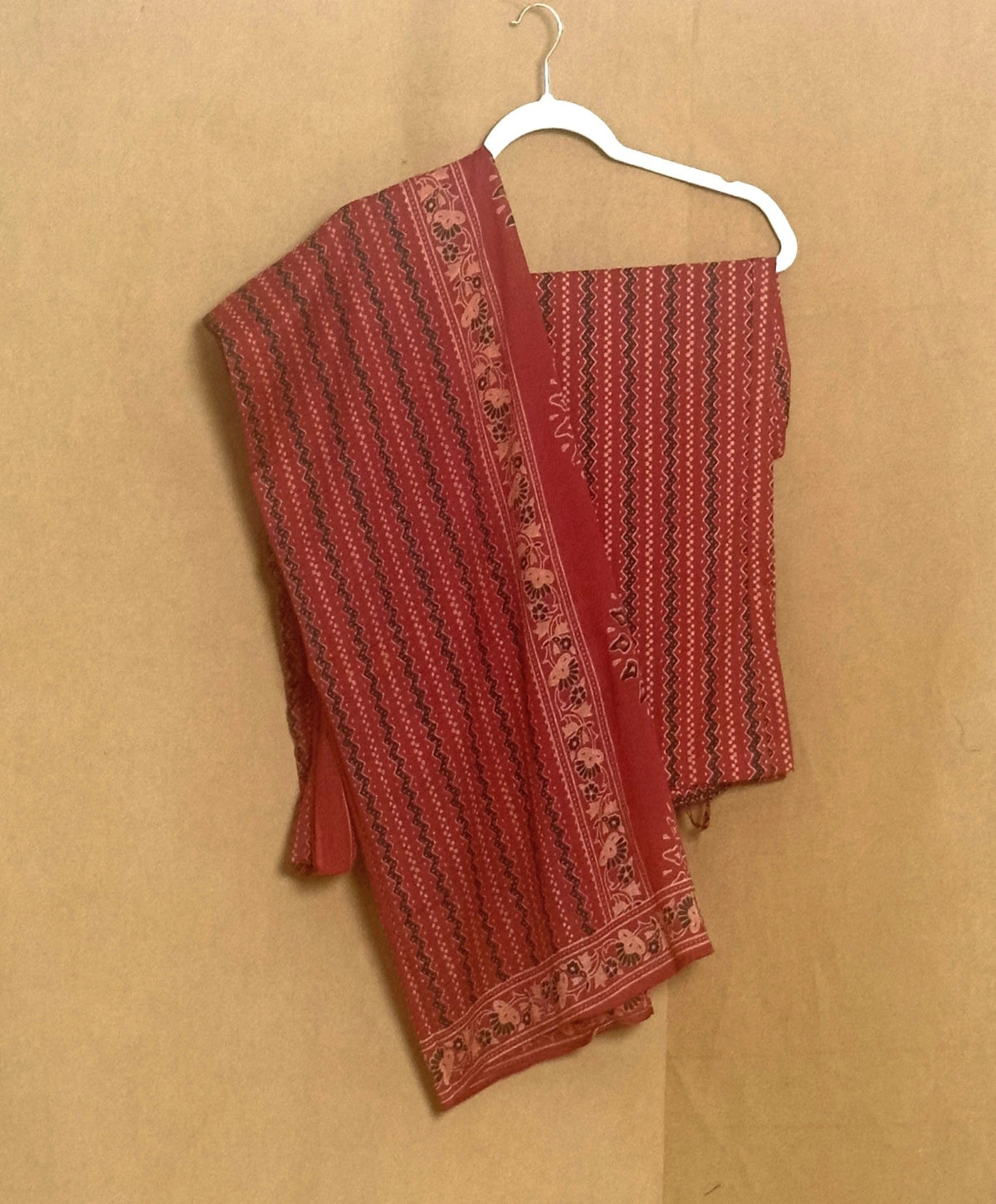 Red patterned fabric on a hanger against a beige background