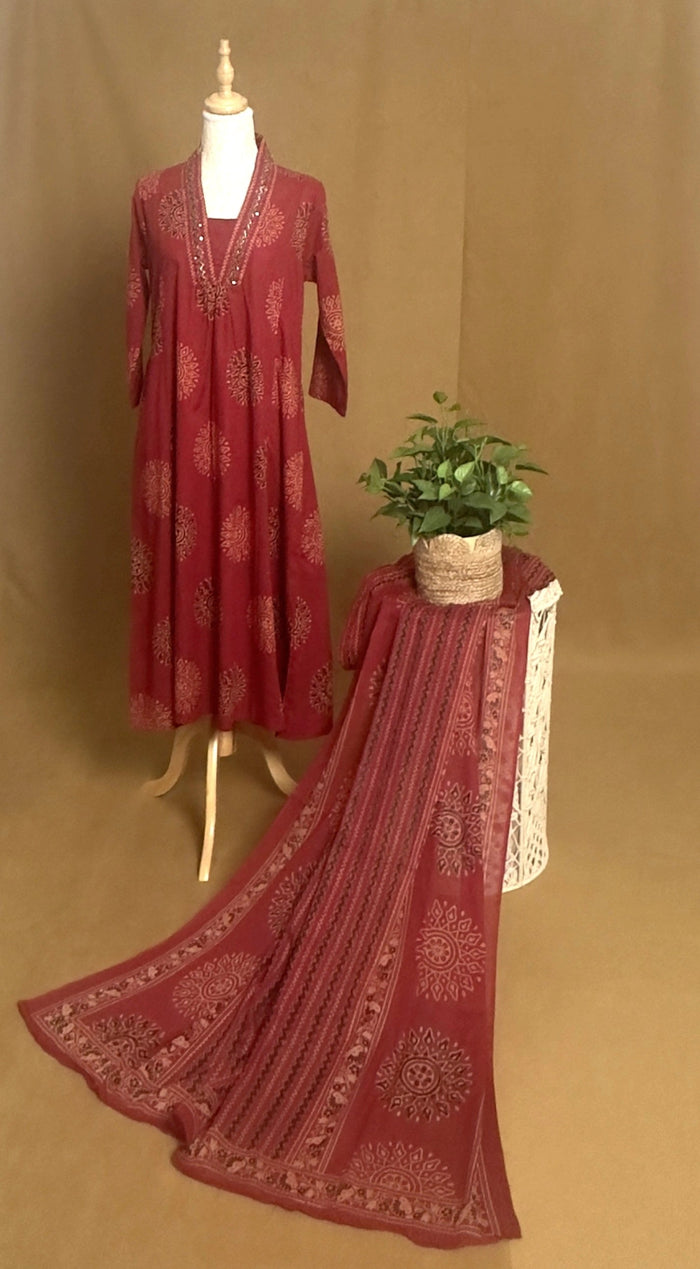 Red embroidered dress on a mannequin with a matching scarf on a brown background