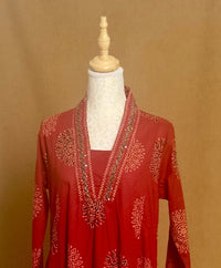 Red embroidered dress on a mannequin against a brown background