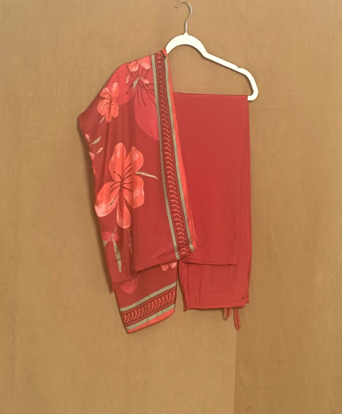 Red floral outfit on a hanger against a brown background