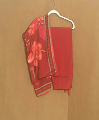 Red floral outfit on a hanger against a brown background