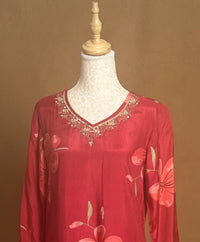 Red floral dress with lace neckline on a mannequin against a brown background