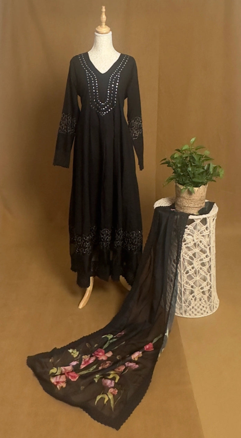 Black embroidered dress on a mannequin with a matching scarf on a brown background