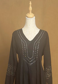 Black dress with silver embellishments on a mannequin against a brown background