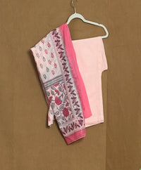 Pink saree with floral patterns on a hanger against a brown background