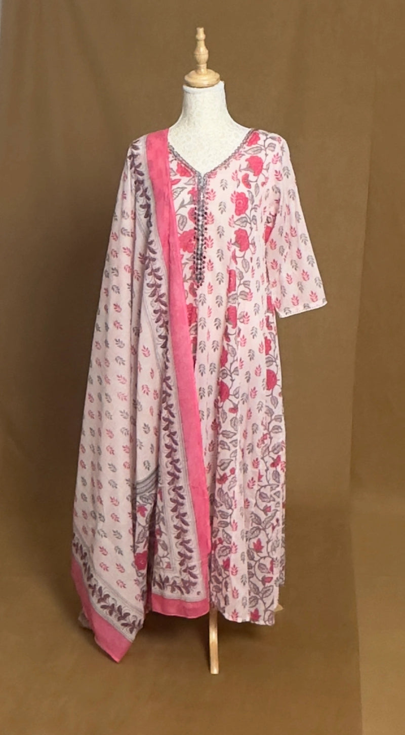 Long floral dress with pink trim on a mannequin against a brown background