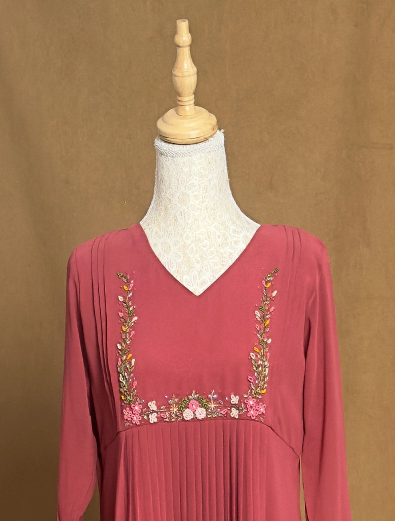 Red dress with floral embroidery on a mannequin against a brown background