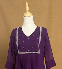 Purple dress with silver embellishments on a mannequin against a brown background