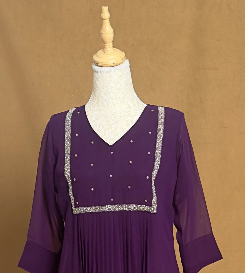 Purple dress with silver embellishments on a mannequin against a brown background