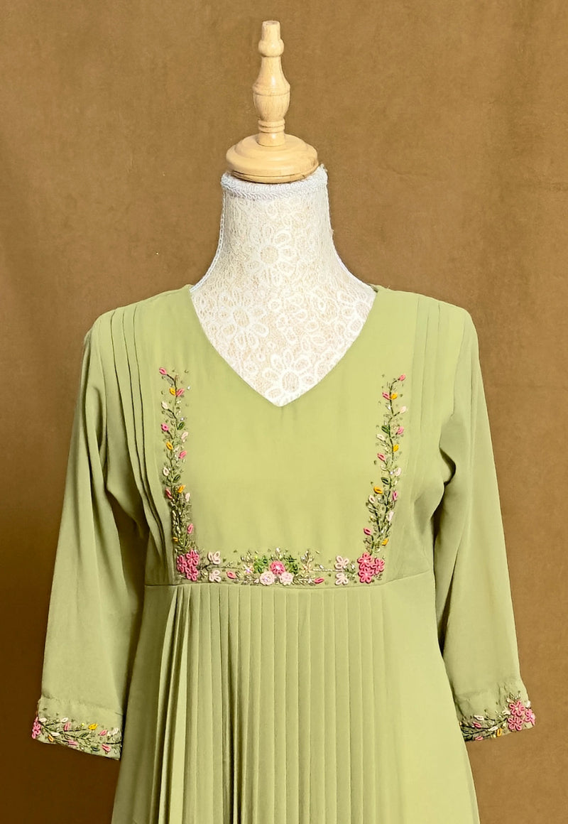 Green dress with floral embroidery on a mannequin against a brown background