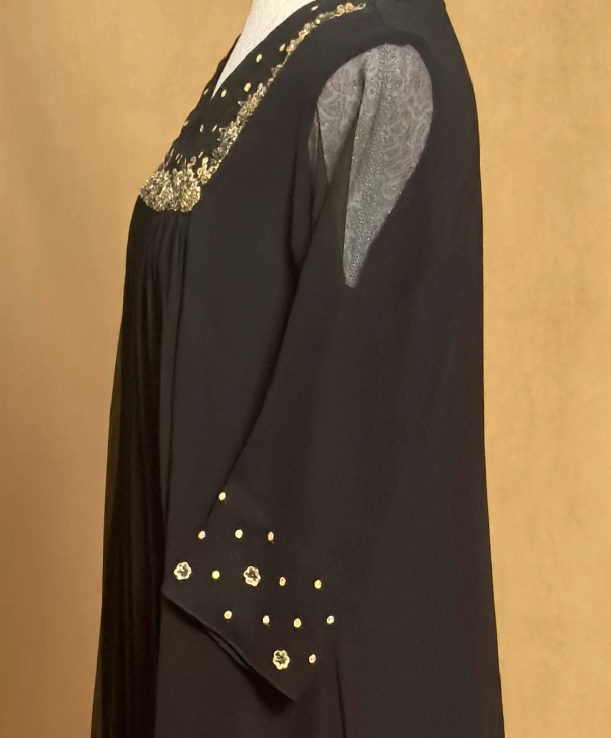 Black garment with gold embellishments on a beige background